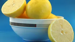 Bílá miska plná citronů na modrém stole